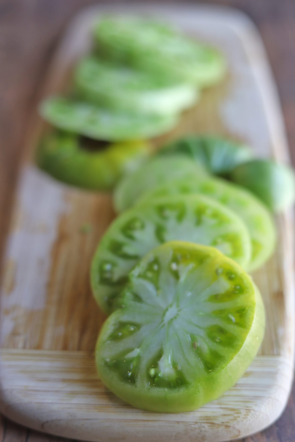 Sliced green tomato on cutting board.