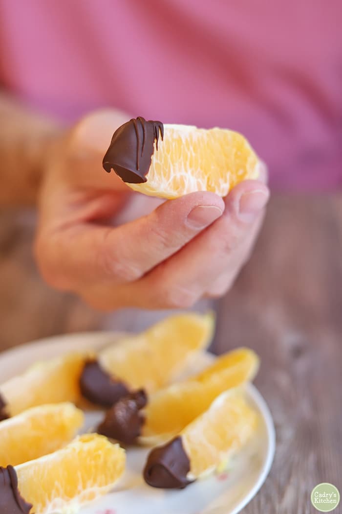 Hand holding chocolate covered orange slice.