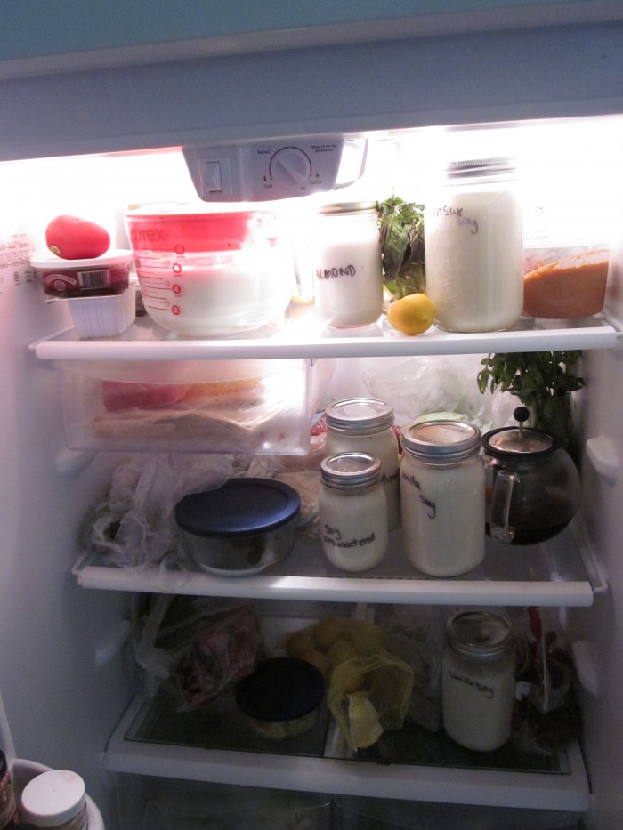 Jars of soy milk in overpacked refrigerator.