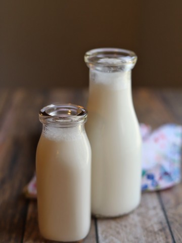Two bottles of homemade almond milk on table.