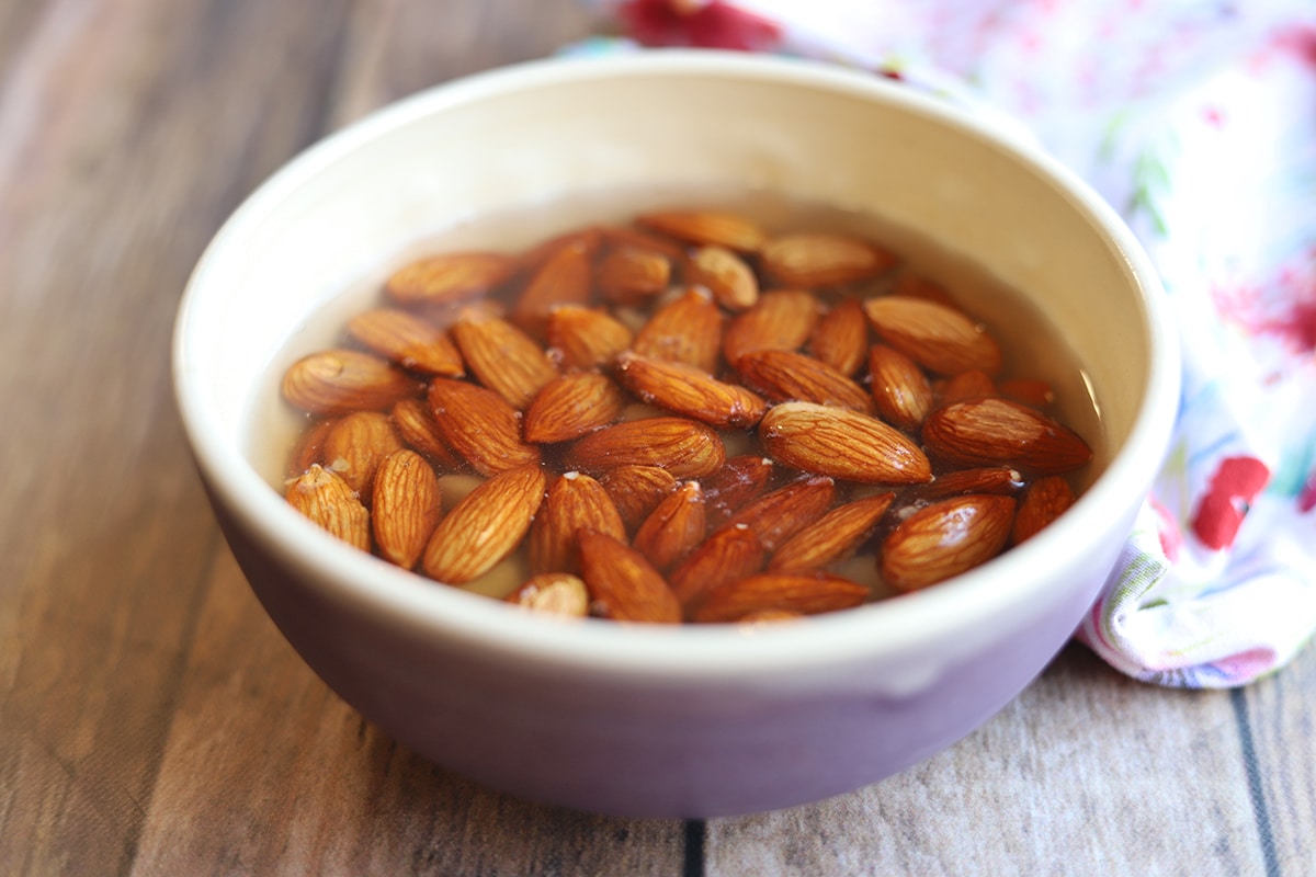 Raw almonds soaking in bowl of water.