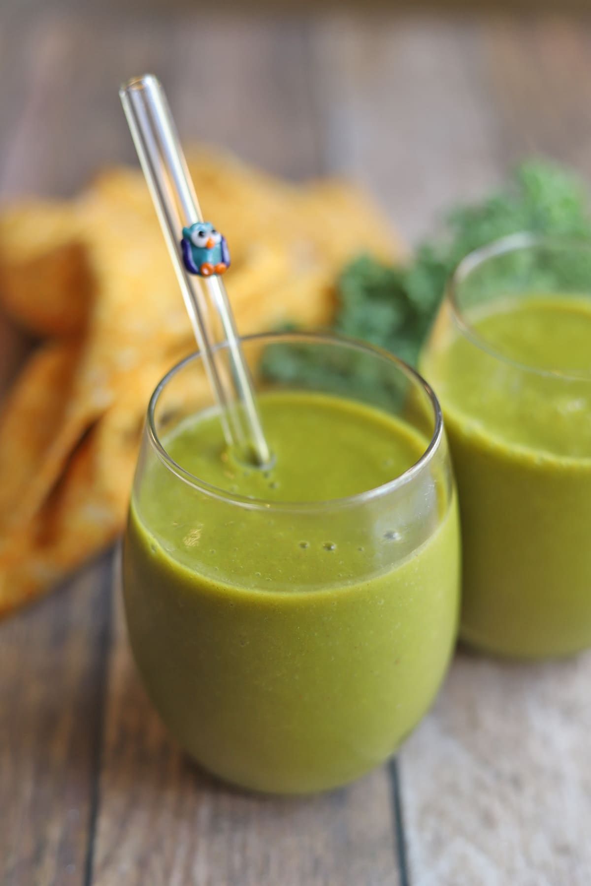 Pumpkin smoothie in glasses by kale leaves.