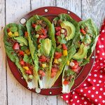 Overhead raw vegan tacos with walnut taco meat, avocado, tomatoes, and bell pepper on plate.