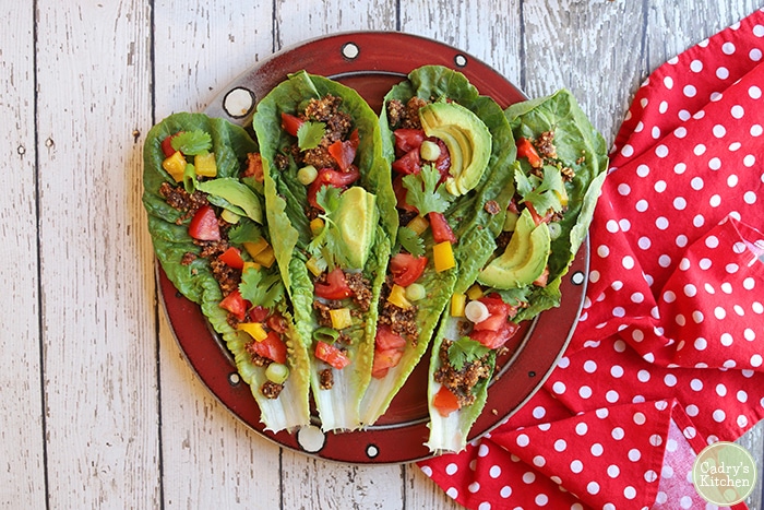 Overhead raw vegan tacos with walnut taco meat, avocado, tomatoes, and bell pepper on plate.