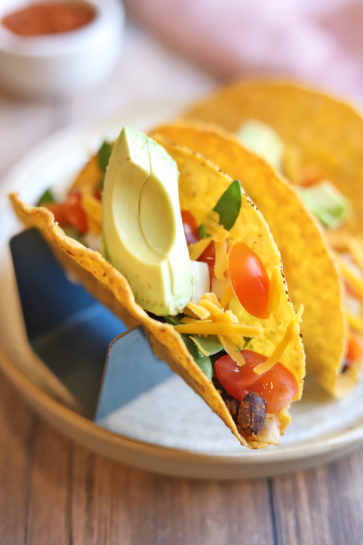 Tacos with avocado and tomatoes in holder.