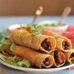 Baked taquitos stuffed with sweet potatoes & black beans on plate and topped with cilantro.