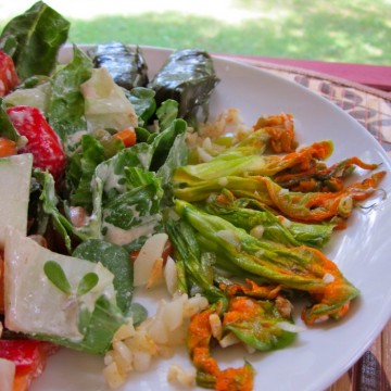 Sauteed squash blossoms on plate by salad.
