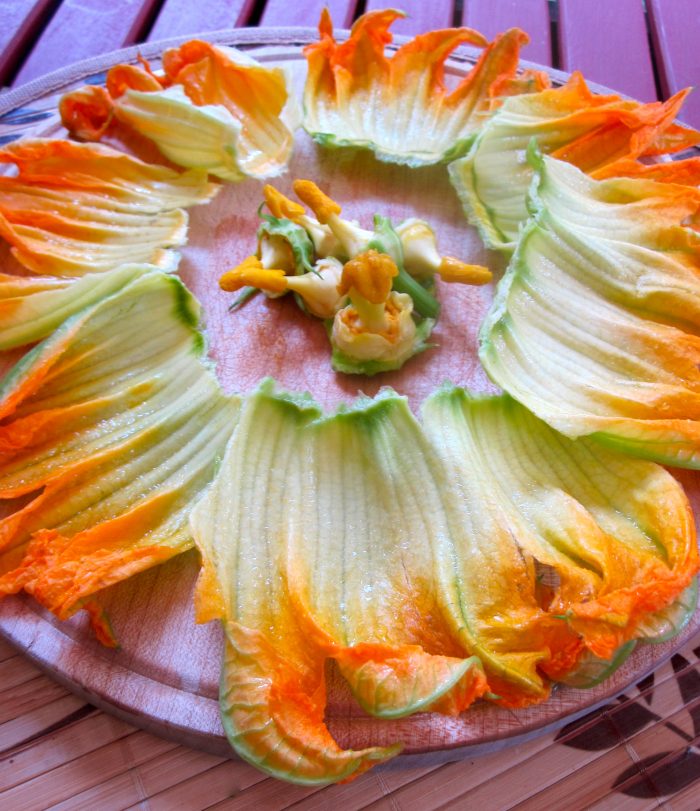 Open squash blossoms with pistils removed on cutting board.