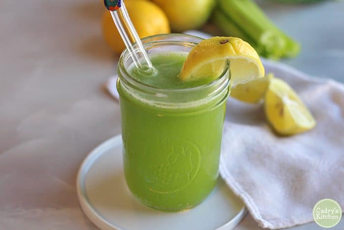 Cucumber celery juice in glass with lemon wedge.