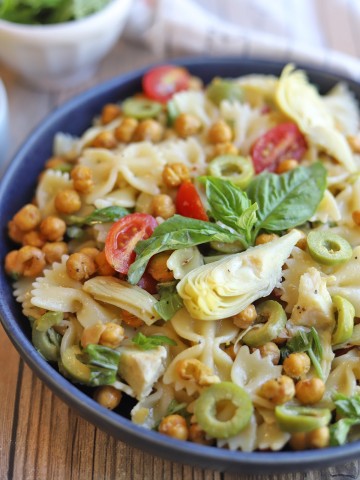 Pasta salad with fresh basil in blue bowl.