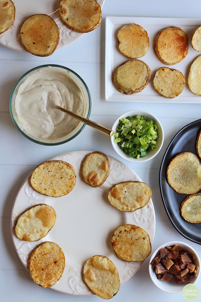 Overhead potato slices, green onions, and cashew cream on table.
