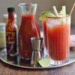 Bloody Mary drink on metal tray with ingredients.