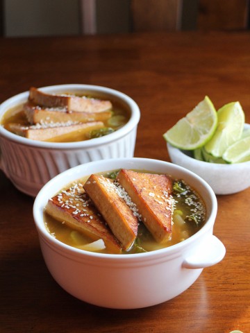 Tofu triangles in soup bowl by lime slices.