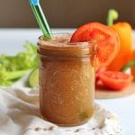 Glass of juice with tomato slice & straw.