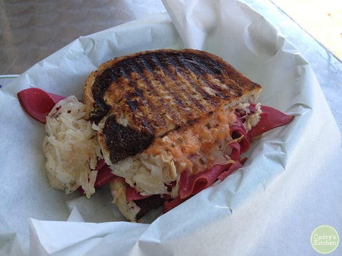 Reuben sandwich with bright pink pastrami in paper lined basket.