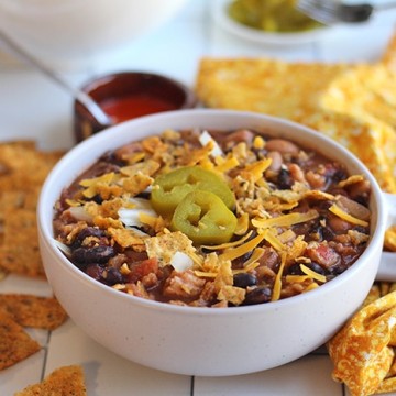Meatless chili with non-dairy cheese and tortilla chips in bowl.