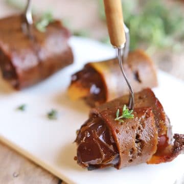 Vegan bacon wrapped dates on appetizer plate.