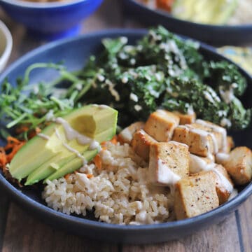 Tofu bowl with avocado, kale chips, and baked tofu on brown rice.