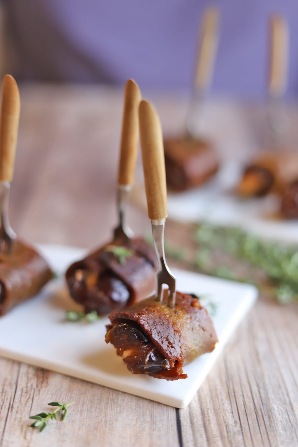 Seitan bacon wrapped dates on appetizer plate.