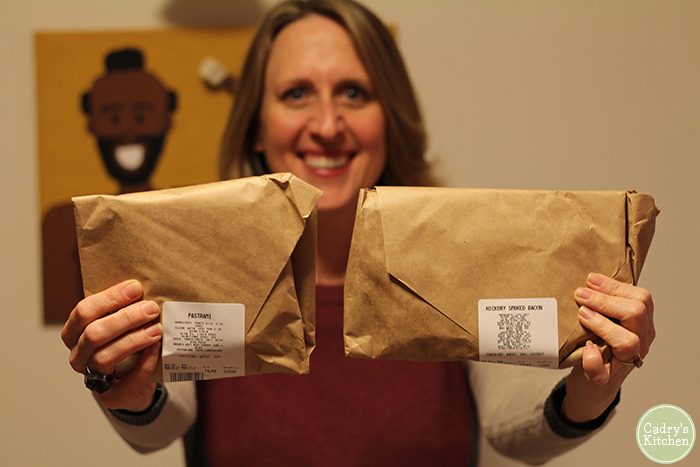 Cadry holding wrapped packages of seitan from the Herbivorous Butcher.