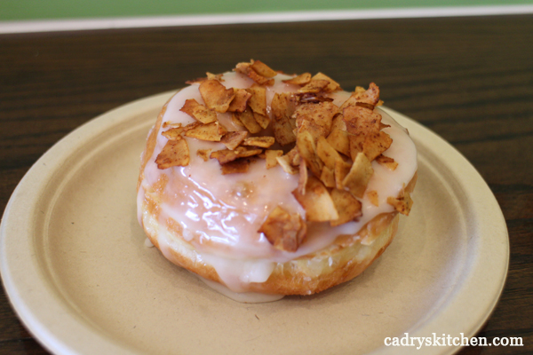 Glazed donut with coconut bacon on plate.
