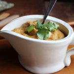 Cauliflower queso in gravy boat with cilantro on top.