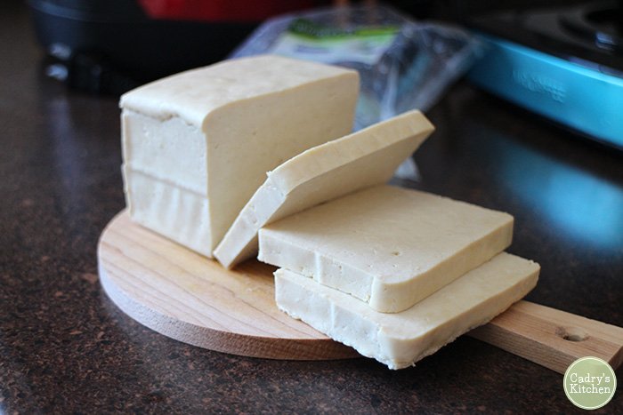 Tofu cut into slices on cutting board.