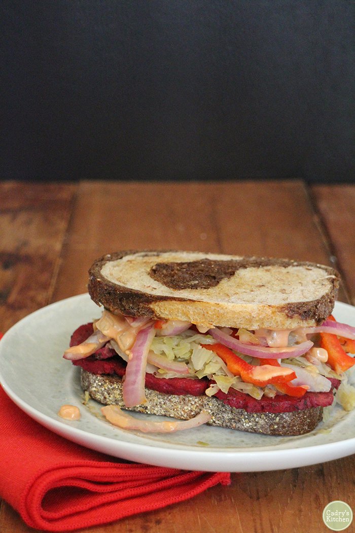Vegan reuben sandwich on plate with red napkin.
