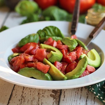 Avocado caprese salad in bowl. Avocado tomato salad with fresh basil.