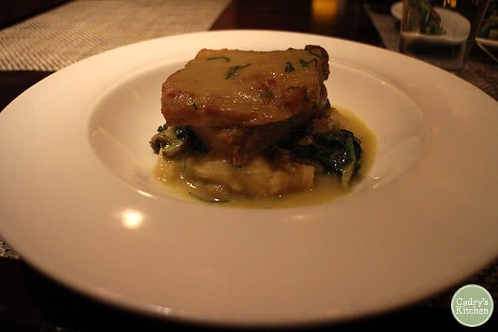 Seitan piccata with creamed spinach over mashed potatoes in bowl.