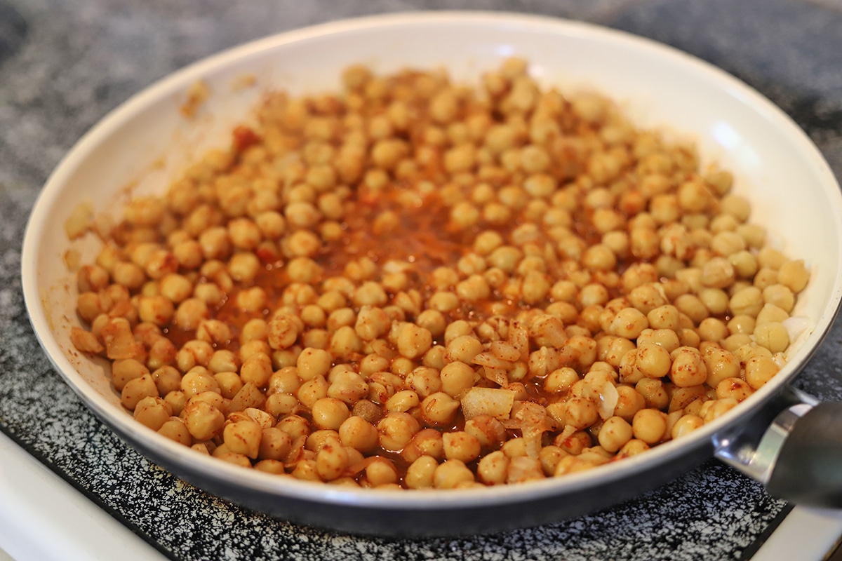 Garbanzo beans in a skillet with water and seasonings.