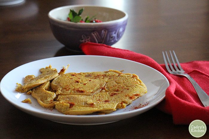 Chickpea flour pancake on plate by red napkin and fork.
