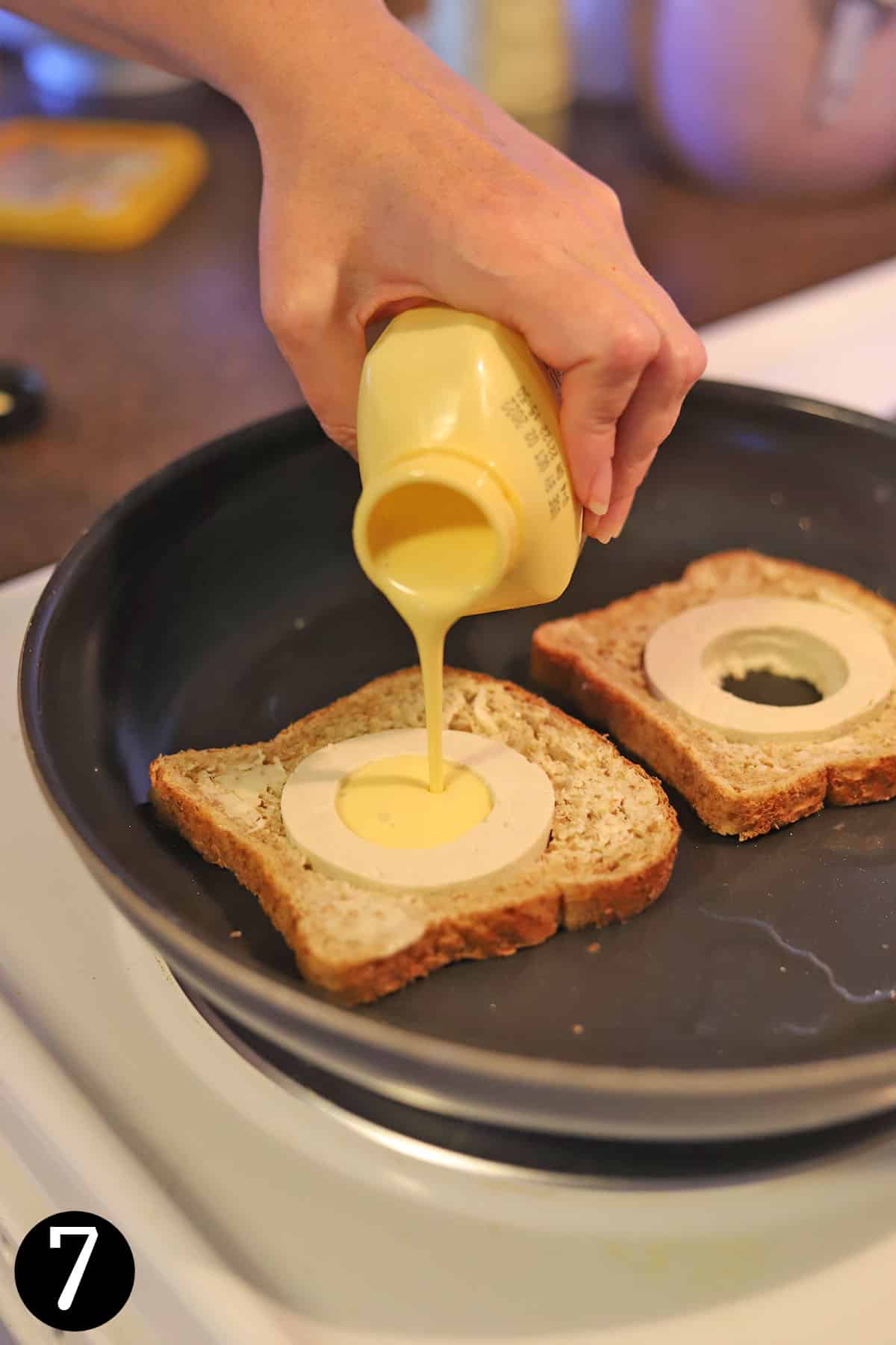 Just Egg being poured into tofu circle in bread slice in skillet.