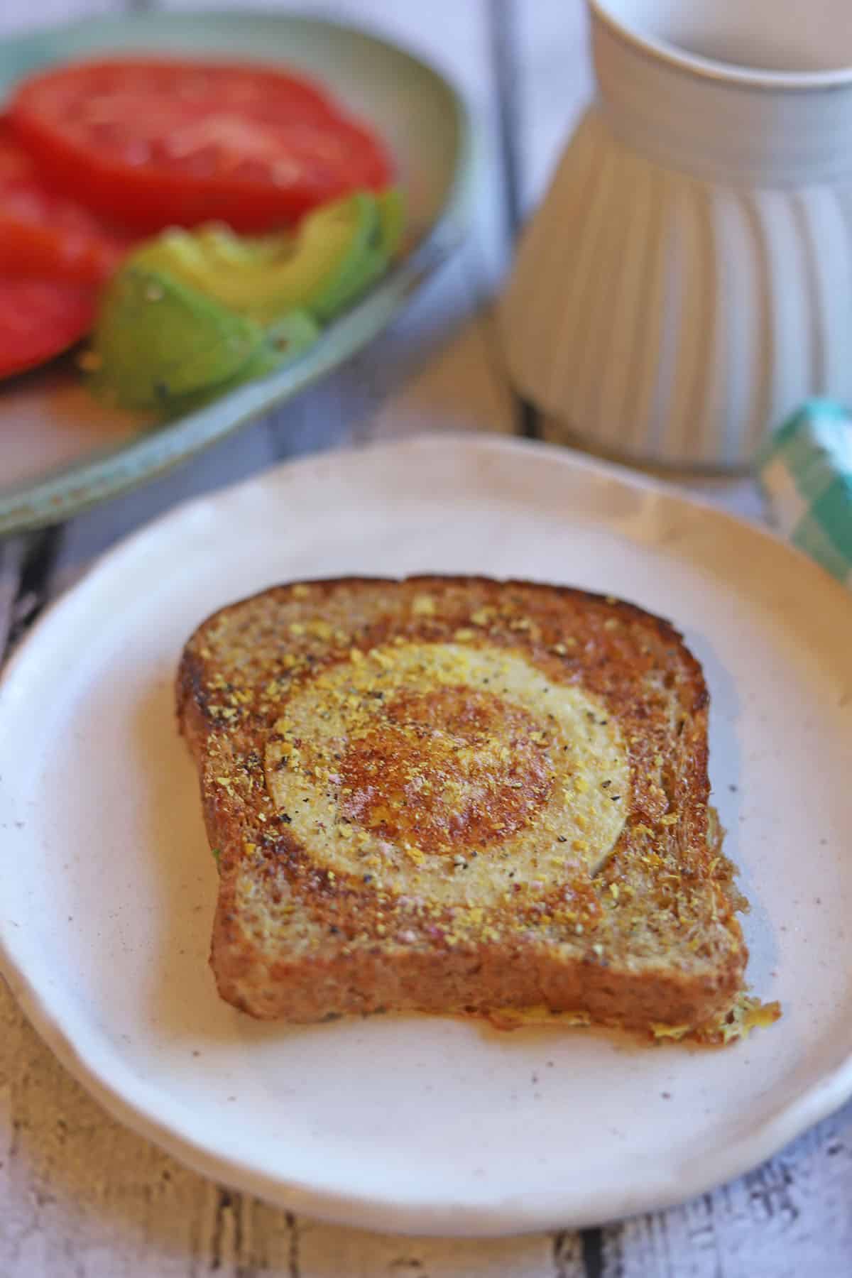Fried vegan egg in toast by coffee cup.