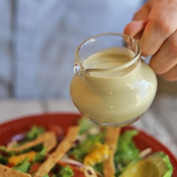 Small pitcher of dressing by salad.