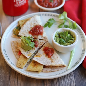 Quesadilla on plate with guacamole and salsa.