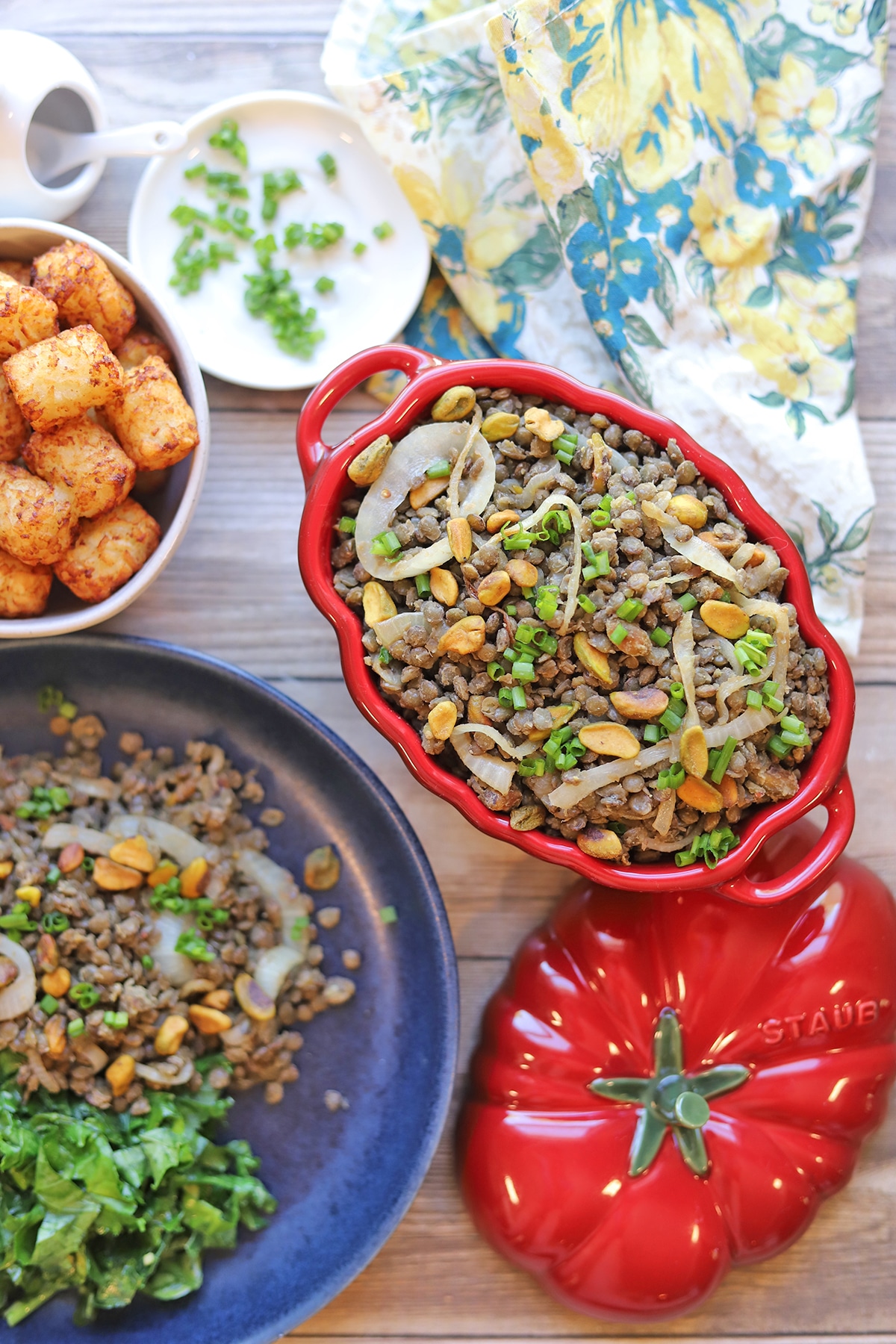 Overhead red serving dish with Puy lentils, tater tots, and kale.