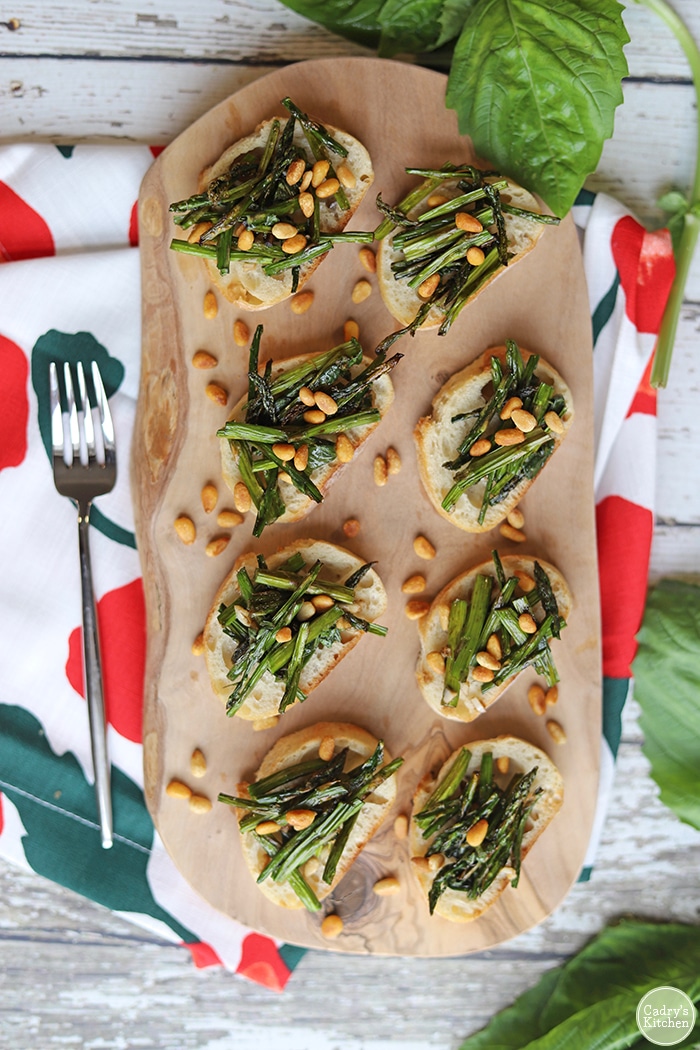 Overhead asparagus appetizers with toasted pine nuts on board.