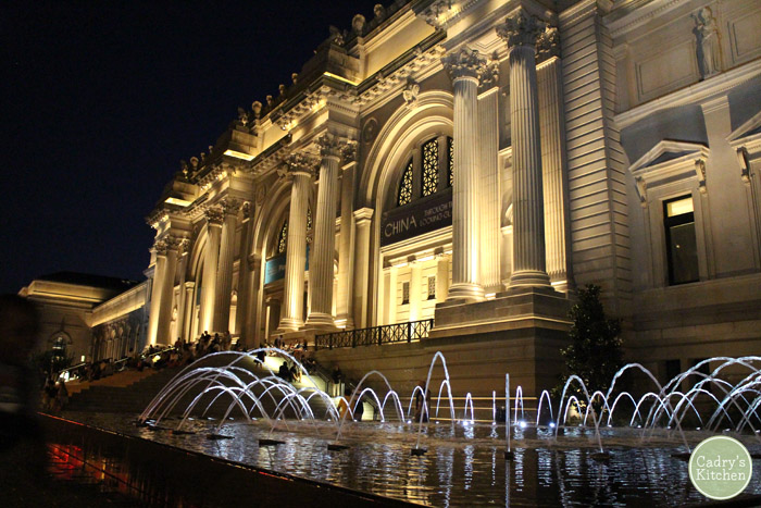 Exterior Metropolitan Museum of Art at night with lit up fountain.
