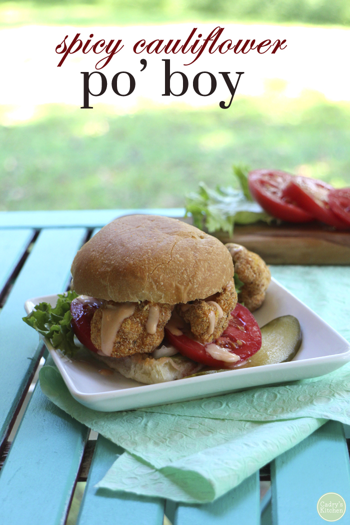 Text overlay: Spicy cauliflower po' boy. Sandwich on plate with pickle.