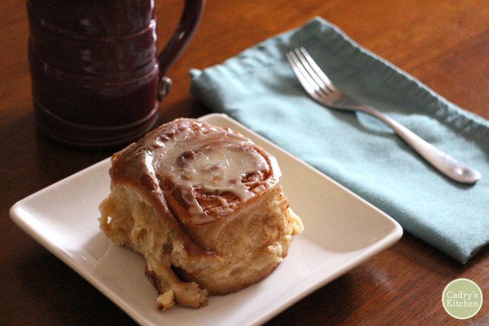 Cinnamon roll on plate by napkin.