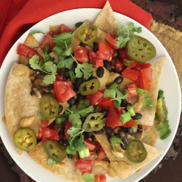 Text: Puffy nachos. Plate of fried vegan nachos covered in toppings.