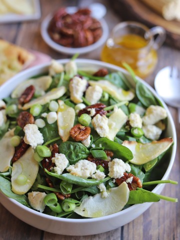 Close-up roasted apple salad with candied pecans and vegan feta.