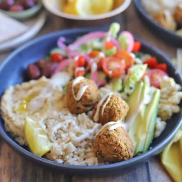 Rice bowl with falafel, salad, and tahini sauce.