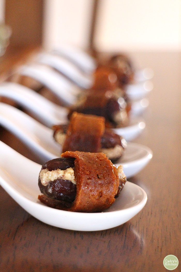 Vegan bacon dates with almond butter on little spoons.