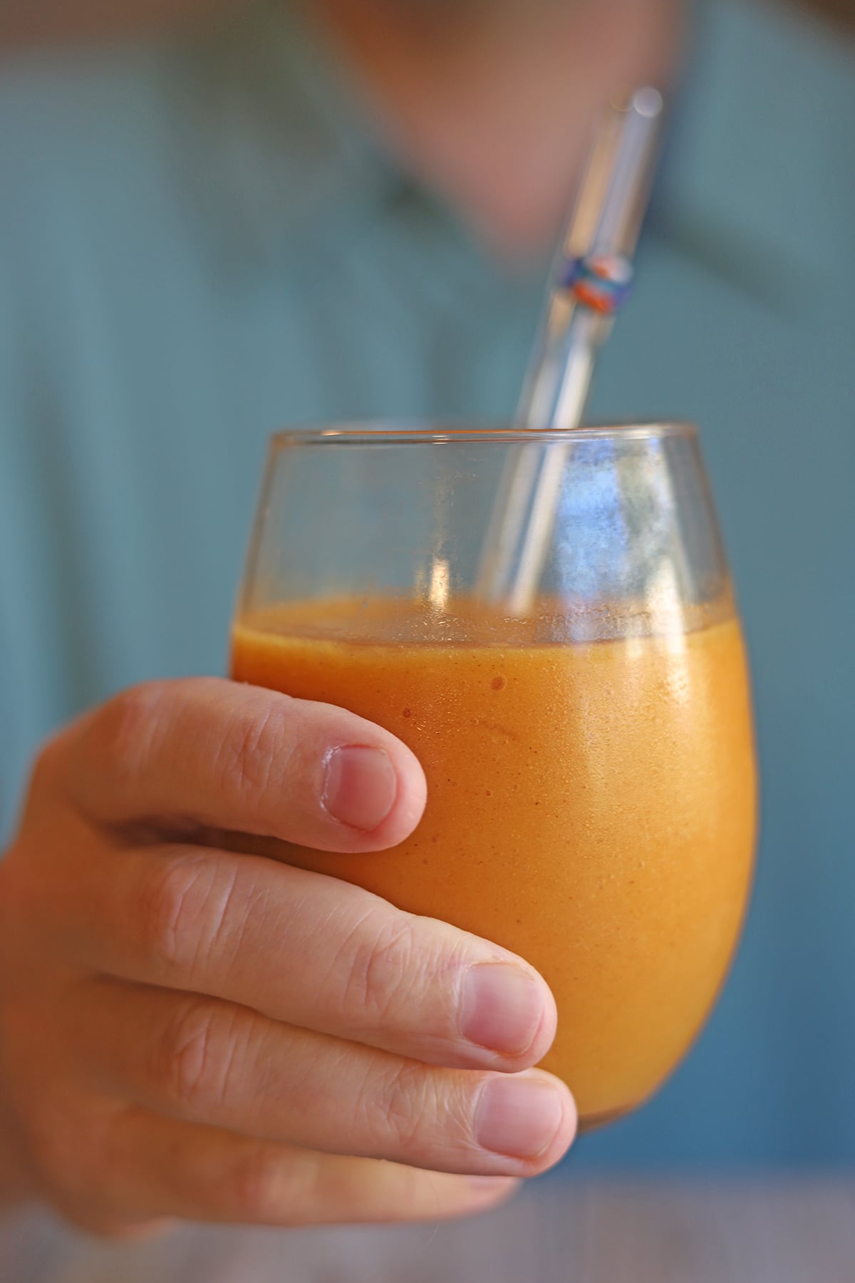 Hand holding glass of sweet potato smoothie.