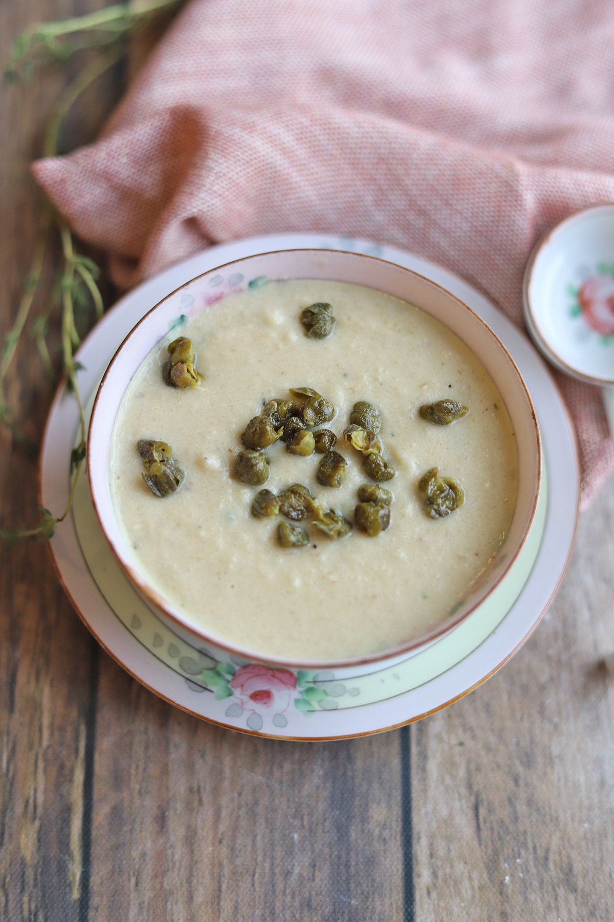 Cauliflower soup with fried capers in bowl.