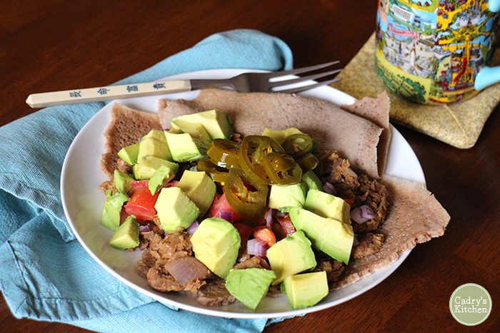 Mashed fava beans with avocado, tomatoes, and jalapeno peppers on injera.