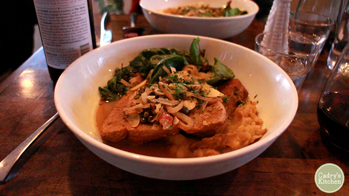Seitan piccata in bowl with potatoes and greens.