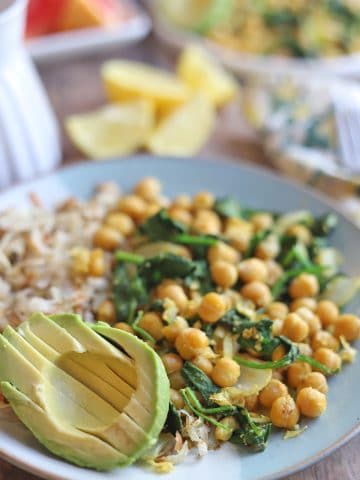 Sliced avocado on plate with chickpea scramble and hashbrowns.